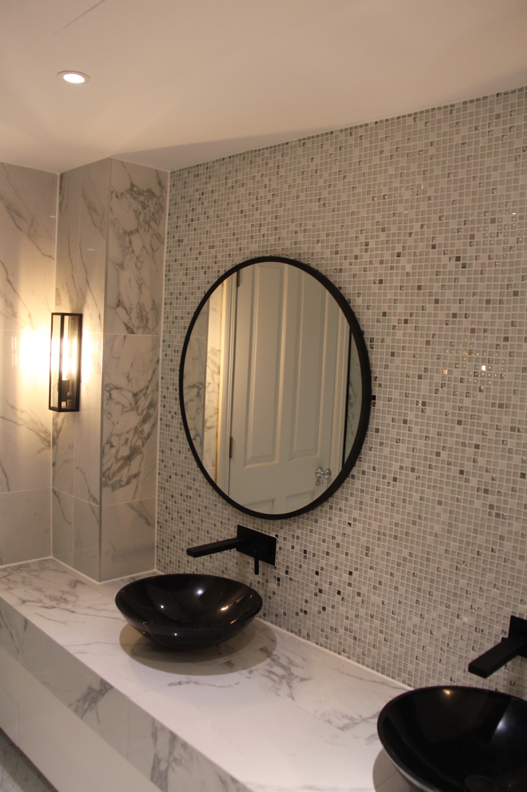 Finished bathroom with marble, mosaic tiling and black basins